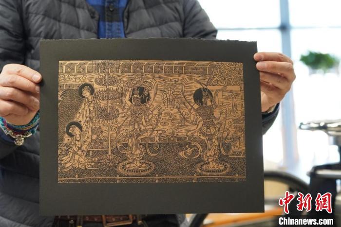 圖為手工書藝人展示敦煌雕版壁畫印刷品。　九美旦增 　攝