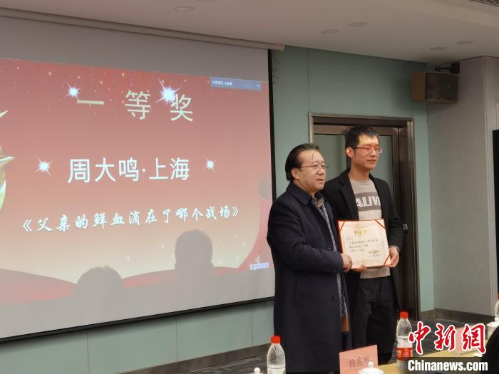 圖為作家、西北師范大學(xué)新聞與傳媒學(xué)院院長(zhǎng)徐兆壽頒發(fā)一等獎(jiǎng)證書(shū)，代領(lǐng)獎(jiǎng)?wù)呱吓_(tái)領(lǐng)獎(jiǎng)?！钅?攝