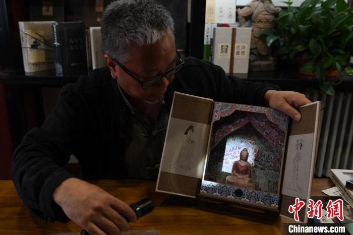 圖為讀者出版集團(tuán)讀者晉林工作室獨(dú)立出品人徐晉林，展示互動性強(qiáng)的敦煌題材手工書。(資料圖) 楊艷敏 攝