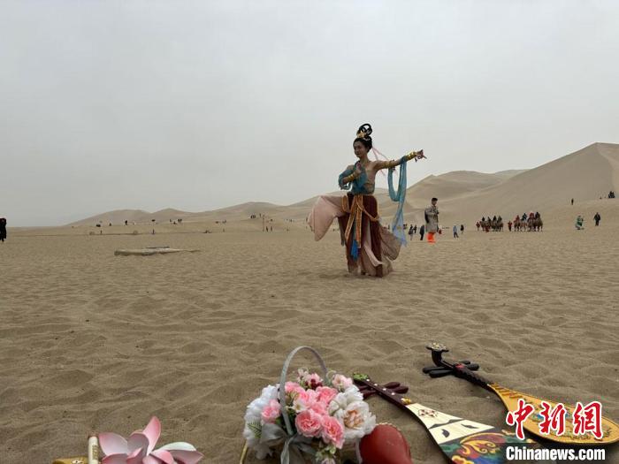 圖為2023年4月底，敦煌大漠“逐舞者”奧楠在鳴沙山月牙泉景區(qū)視頻直播敦煌舞?！●T志軍 攝