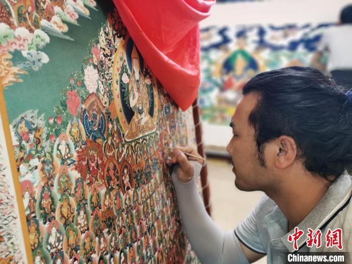 圖為更登才讓的徒弟繪畫唐卡?！?zhí)砀?攝