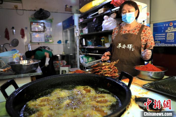圖為平安驛·河湟民俗文化體驗地內(nèi)的商戶炸干板魚?！⊙Φ?攝