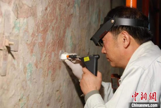 敦煌研究院研究員樊再軒進(jìn)行壁畫修復(fù)。(資料圖)張?jiān)莆?攝